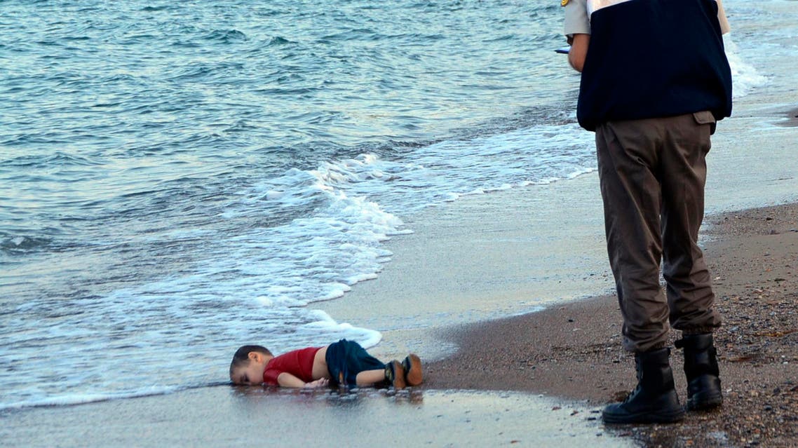 A paramilitary police officer investigates the scene before carrying the lifeless body of 3-year-old Aylan Kurdi from the sea shore, near the beach resort of Bodrum, Turkey, early Wednesday, Sept. 2, 2015.
