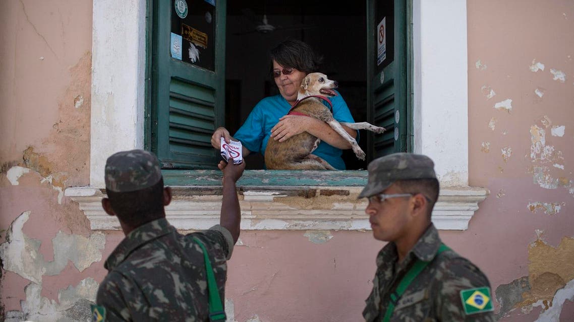 Brazilian Army soldiers distribute flyers with information on how to combat the Aedes aegypti during the "Burial of the Mosquito" carnival block parade in Olinda, Pernambuco state, Brazil, Friday, Feb. 5, 2016. AP