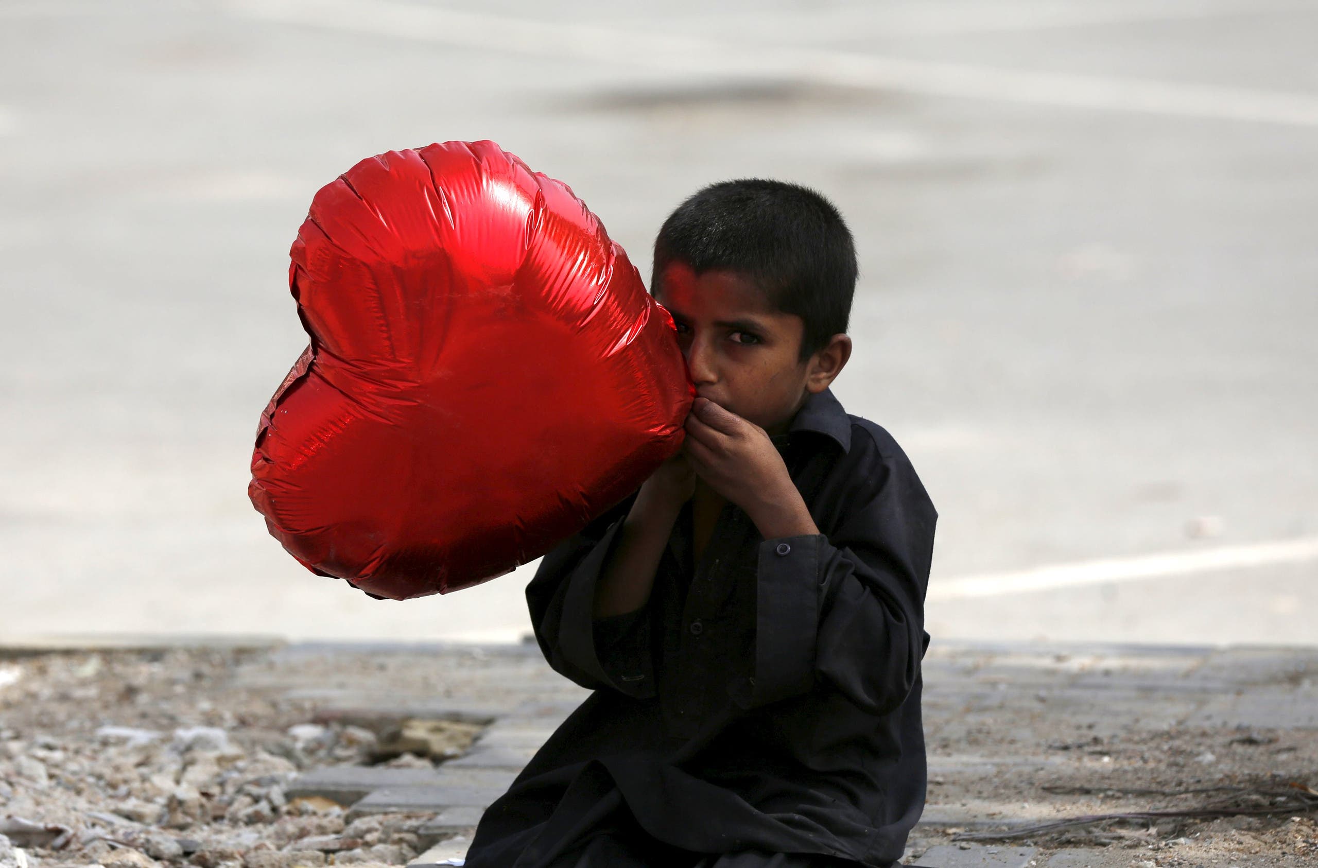 A boy inflates a heart-shaped balloon to sell on Valentine's Day in Karachi, Pakistan February 14, 2016. (Reuters)
