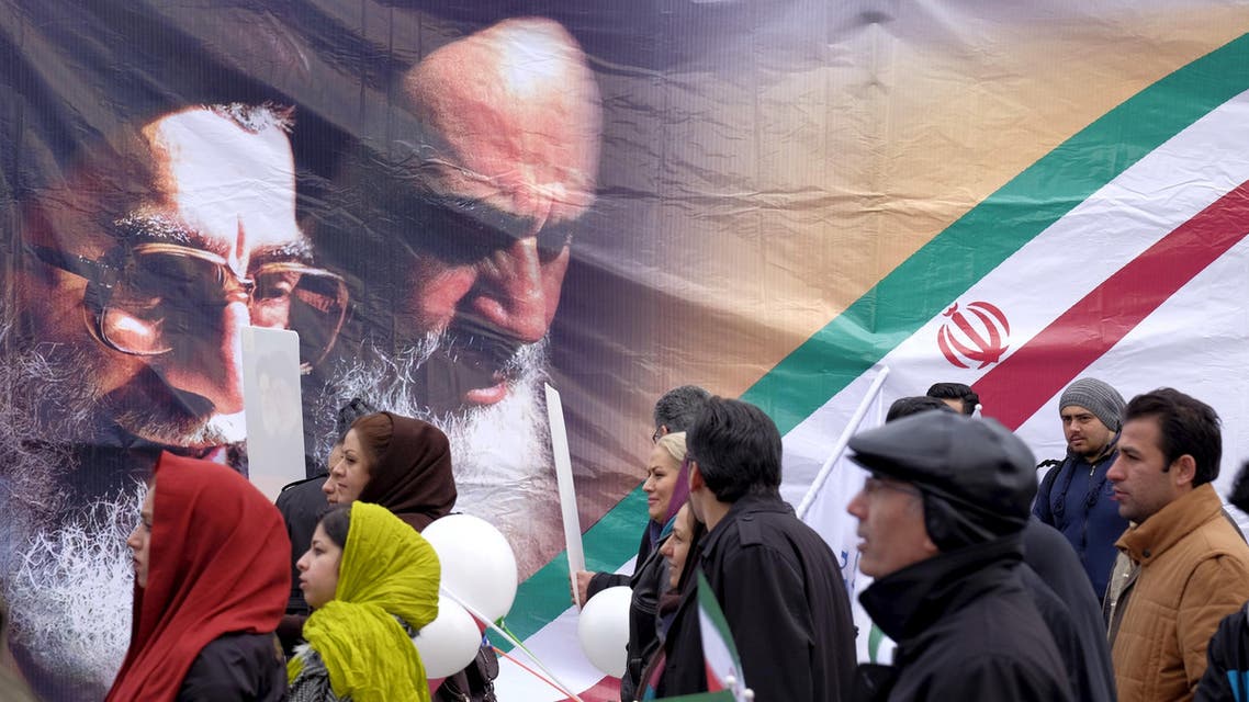 People walk past a large picture of the late leader of the Islamic Revolution Ayatollah Ruhollah Khomeini (R) and Iran's Supreme Leader Ayatollah Ali Khamenei, during a ceremony marking the 37th anniversary of the Islamic Revolution, in Tehran February 11, 2016. REUTERS
