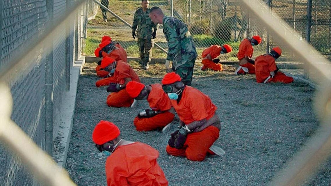 Detainees wearing orange jump suits sit in a holding area as military police patrol during in-processing at the temporary detention facility Camp X-Ray on Guantanamo Bay U.S. Naval Base in Cuba. (AP)