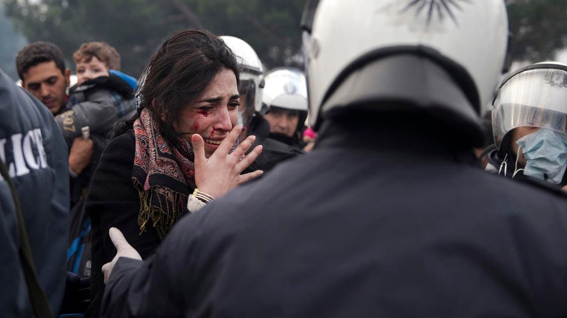 A bleeding woman reacts after a rock was thrown at her a little before crossing into Macedonia at the northern Greek border station of Idomeni, Friday, Dec. 4, 2015. (AP)