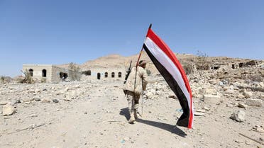A pro-government army soldier carries Yemen's national flag as he walks at the strategic Fardhat Nahm military camp, around 60km  from Yemen's capital Sanaa. (Reuters)