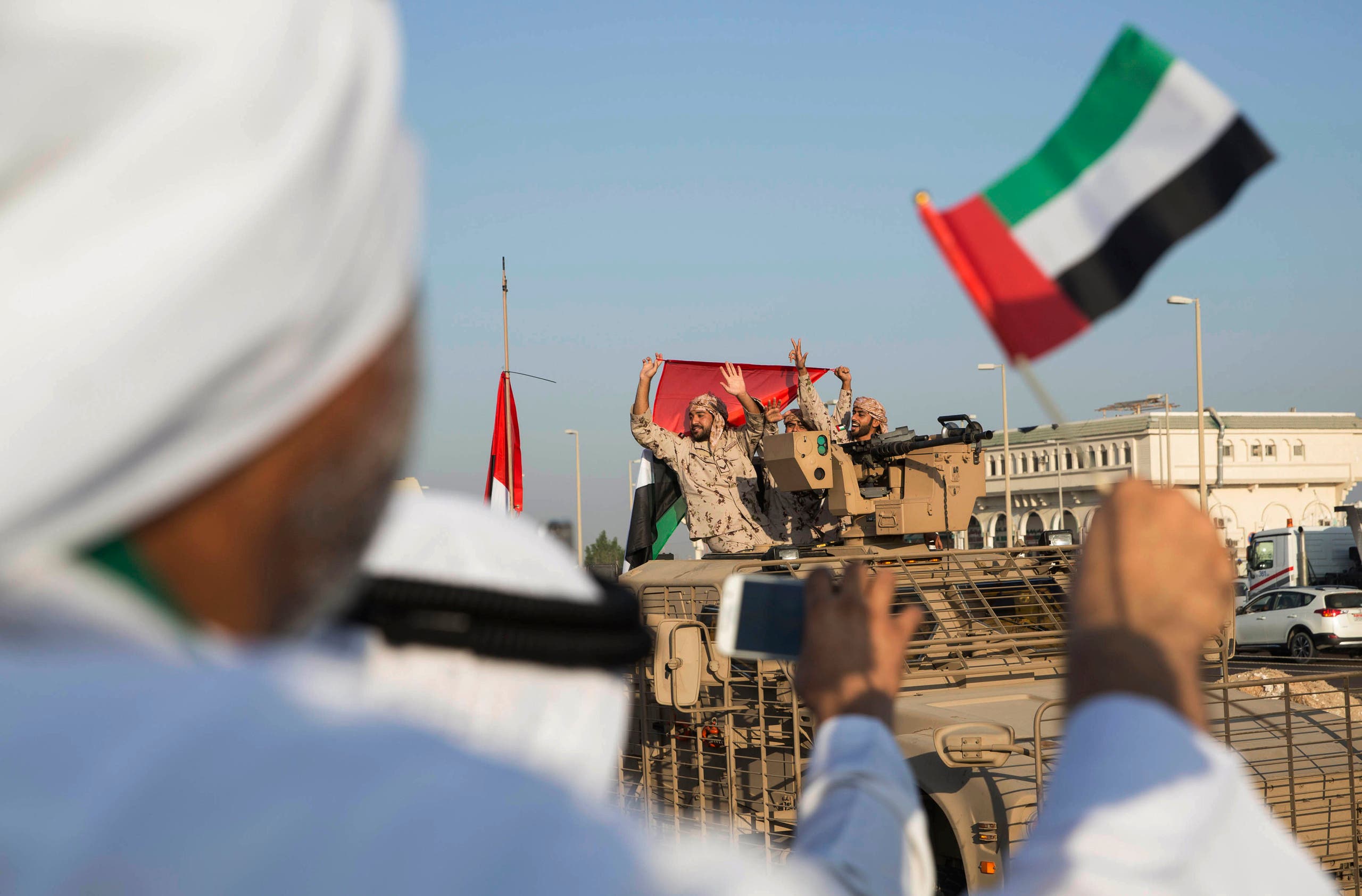 Emirati people wave the national flag as a convoy of UAE military vehicles and personnel travels from a UAE army base marking their retuurn from Yemen, United Arab Emirates, Saturday, Nov. 7, 2015. (AP)