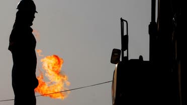 A gas flame burns behind oil field workers in the desert oil fields of Sakhir, Bahrain. (AP)