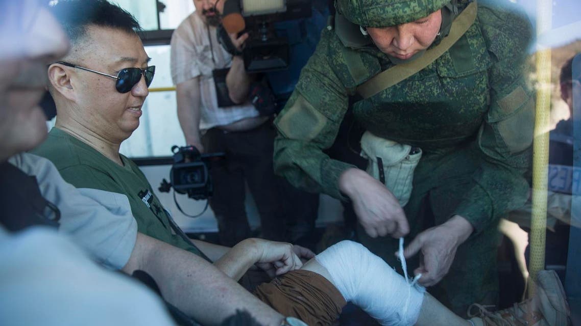 A Chinese reporter is bandaged by Russian military officer after he fell while moving to safety during explosions in Kinsibba, Syria, near the border with Turkey. (AP)