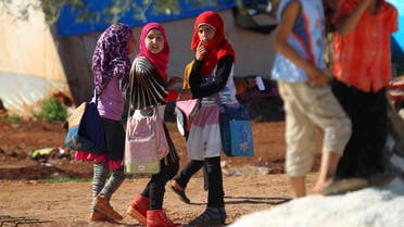 Internally displaced Syrian girls carry school bags inside Safsafa camp, northern Idlib countryside. (Reuters)