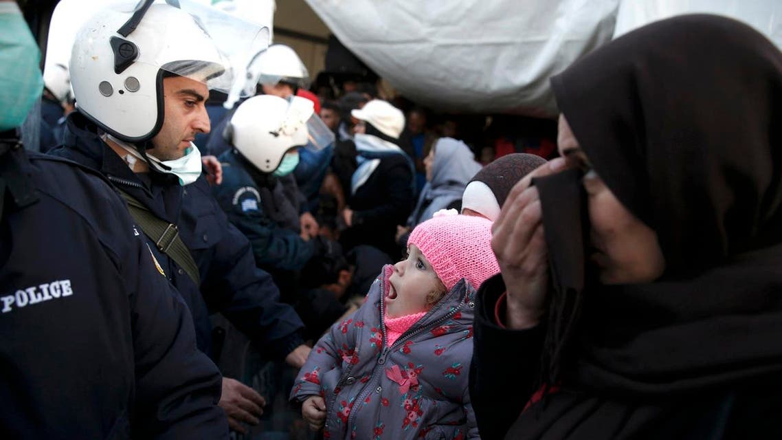 Migrants who are waiting to cross the Greek-Macedonian border, stand in front of police officers in a makeshift camp, near the Greek village of Idomeni March 2, 2016. (Reuters)