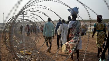 In this photo taken Tuesday, Jan. 19, 2016,displaced people walk next to a razor wire fence at the United Nations base in the capital Juba, South Sudan. AP