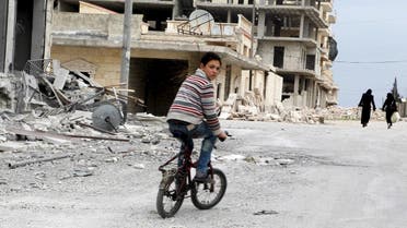 A boy rides a bicycle near damage in Kafr Hamra village, northern Aleppo countryside, Syria February 27, 2016. Picture taken February 27, 2016. REUTERS/Abdalrhman Ismail