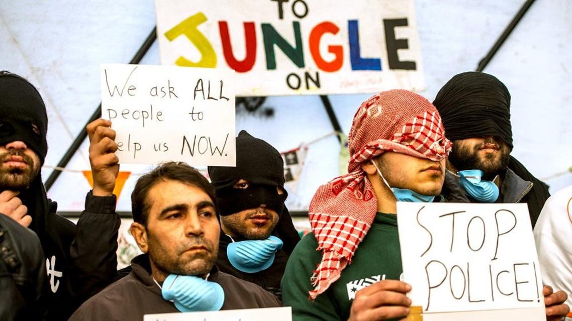 Iranian migrants with their lips sewn shut hold signs at the "Jungle" migrant camp in the French port city of Calais on March 4, 2016 (AFP)
