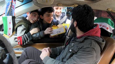 Boys try to sell biscuits to a man driving a car in Aleppo. (Reuters)