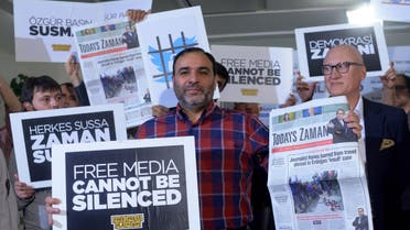 Bulent Kenes, editor-in-chief of Today's Zaman, shows his newspaper minutes before police detain him in his office in Istanbul, Turkey, late Friday, Oct. 9, 2015. 