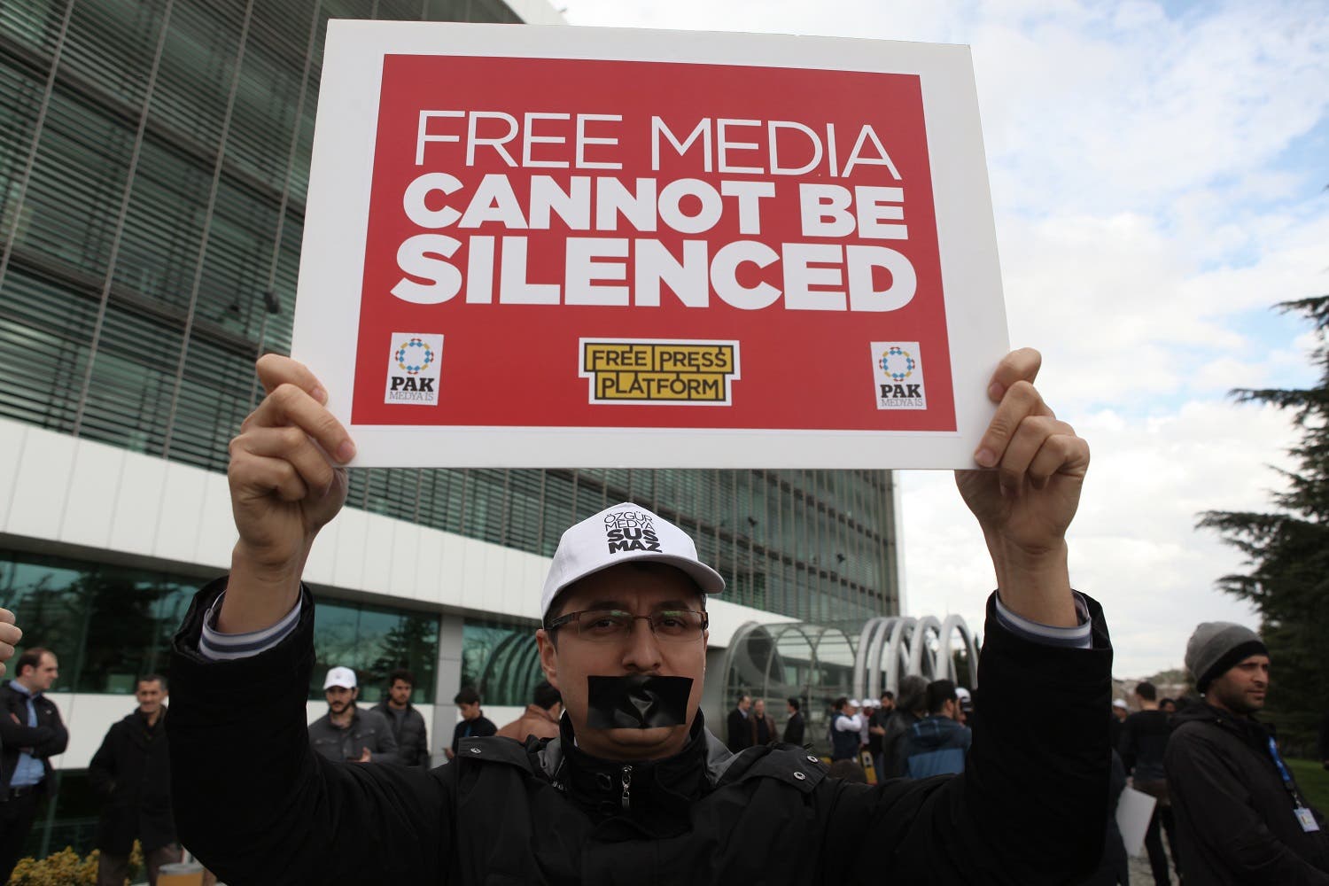 A man holds up a placard as he gathers in solidarity outside Zaman newspaper in Istanbul, Friday, March 4, 2016 after a local court ordered that Turkey's largest-circulation, opposition newspaper, which is linked to a U.S.-based Muslim cleric, be placed under the management of trustees _ a move that heightens concerns over deteriorating press freedoms in Turkey. AP