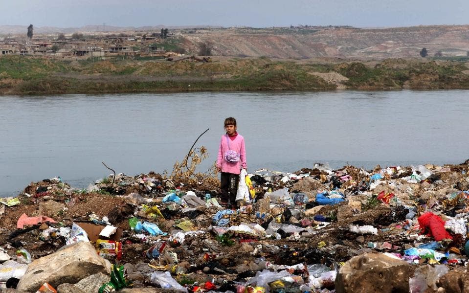 An Iraqi girl stands amid garbage on the banks of the Tigris River in the village of Wana, some 10 kms south of the Mosul Dam (AFP)