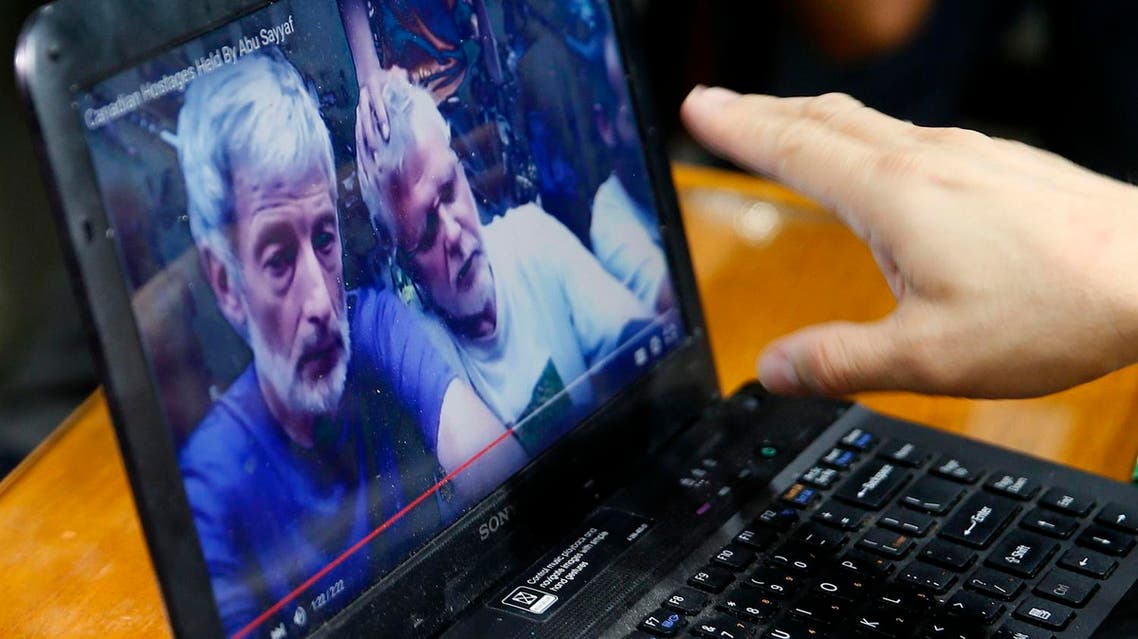 In this Oct. 14, 2015 file photo, Col. Restituto Padilla, spokesman of the Armed Forces of the Philippines, watches a video purportedly showing for the first time two Canadians, a Norwegian and a Filipino woman who were abducted last month from a southern Philippines resort, following a press conference at Camp Aguinaldo at suburban Quezon city, northeast of Manila, Philippines. Militants from at least four small but violent Muslim insurgent groups in the Philippines pledged support last year to the Islamic State group and its leader, Abu Bakr al-Baghdadi, mostly in videotaped messages posted on the Internet. Philippine security officials say they have found no clear evidence so far of a direct link and active collaboration between Islamic State extremists and any of the groups: Abu Sayyaf, the Bangsamoro Islamic Freedom Movement, Rajah Solaiman Movement and the Ansar Khalifa. Islamic State-inspired black flags, however, are visible in a video released this week, purportedly by Abu Sayyaf, of four Western and Filipino hostages kidnapped last month in the southern Philippines. (AP Photo/Bullit Marquez, File)