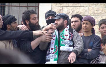Al-Nusra militants grab at the microphone held by poet Hani Allahlah during a protest in Maarat al Noaman