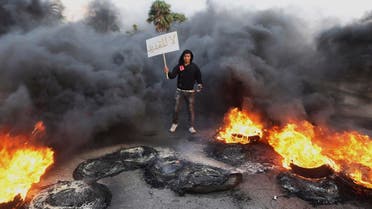 A man holds a sign which reads, "Not extendable" amid smoke and fire after angry protesters set tyres on fire in a street during a demonstration against the General National Congress (GNC) in Benghazi February 21, 2014. (File photo: Reuters)