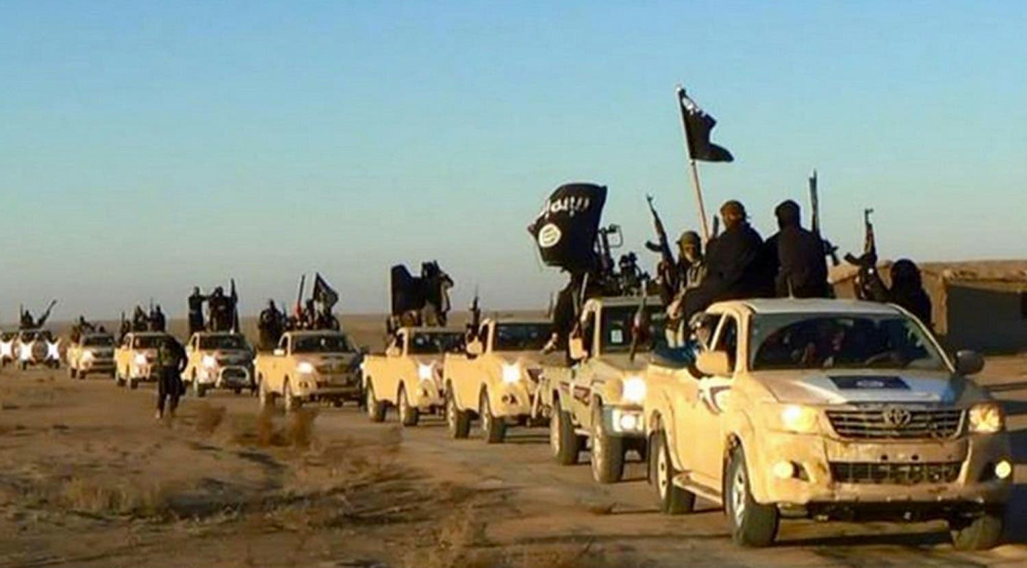 In this undated file photo released online in the summer of 2014 on a militant social media account, which has been verified and is consistent with other AP reporting, militants of the Islamic State group hold up their weapons and wave its flags on their vehicles in a convoy on a road leading to Iraq, in Raqqa, Syria. (Militant photo via AP, File)