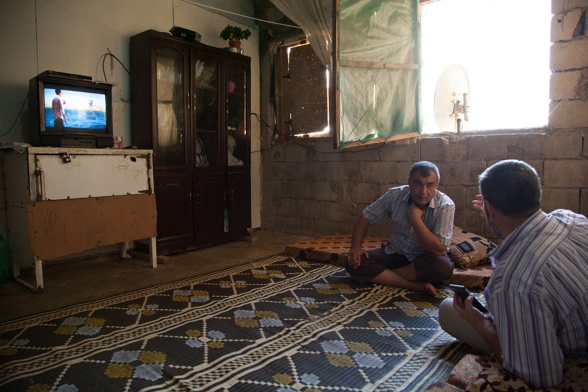 Abu Hafez  speaking with a friend in his one room home in the half built university complex in South Lebanon. (James Haines-Young, Al Arabiya English)