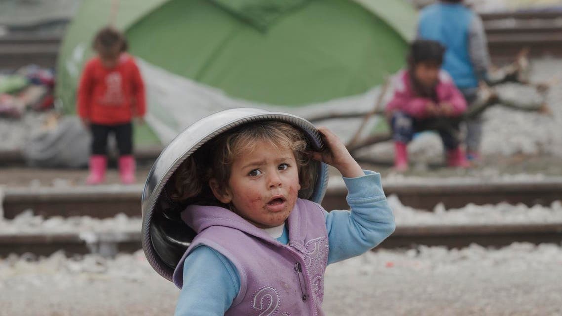A girl of a migrant family walks holding a metal bowl on her head in the make shift refugee camp at the northern Greek border point of Idomeni, Greece, Thursday, March 17, 2016. Leaders of the EU's 28 divided nations reconvene in Brussels in hopes of ironing out disagreements on a proposed agreement with Turkey in the migrants crisis. (AP)