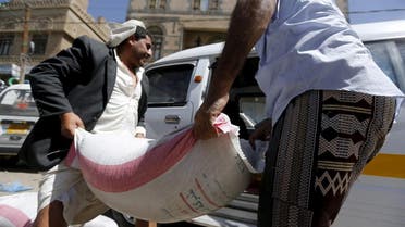 People carry a sack of wheat to a van outside a food distribution center for poor families in Yemen capital Sanaa in this March 17, 2016  (Reuters)