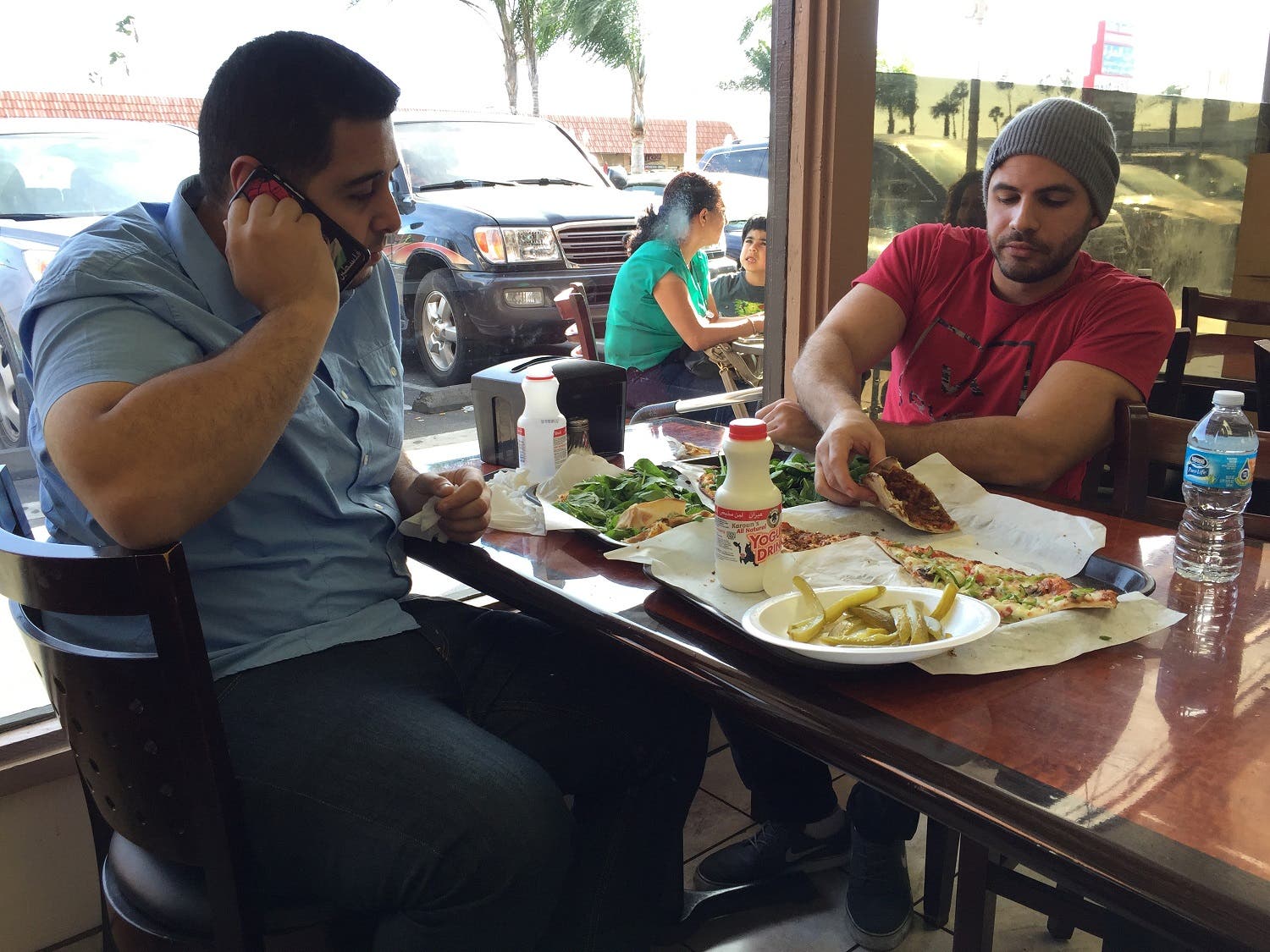 Nas Juma, 22, left, and Omar Ghanim, 23, enjoy Lebanese pizza at Forn Al Hara restaurant in Orange County's Little Arabia in Anaheim, Calif., Tuesday, March 22, 2016. (AP)