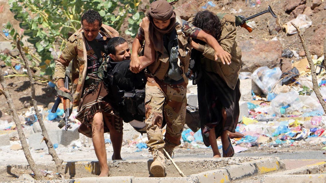 Fighters from local resistance units carry a fellow fighter who was injured in clashes between local fighters and Houthis in March 2016 (AP)