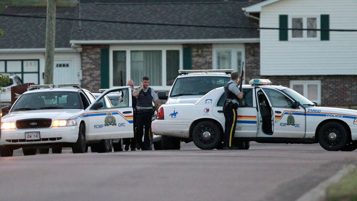 Royal Canadian Mounted Police officers take cover behind their vehicles in Moncton, New Brunswick, on Wednesday, June 4, 2014. AP