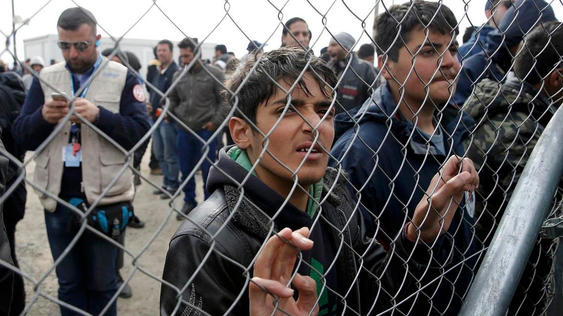 Migrants and refugees stand by a fence at a makeshift camp at the Greek-Macedonian border near the village of Idomeni, Greece, March 27, 2016. (Reuters)