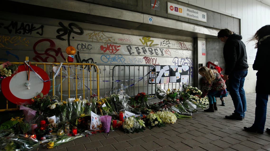 People stop and look at floral tributes placed outside the Maelbeek metro station, the scene of one of the bomb attacks on the Belgian capital, in Brussels, Saturday, March 26, 2016. (AP)