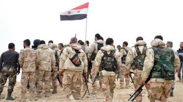 In this photo released by the Syrian official news agency SANA, Syrian soldiers gather around a Syrian national flag in Palmyra, Syria, Sunday, March 27, 2016. (AP)