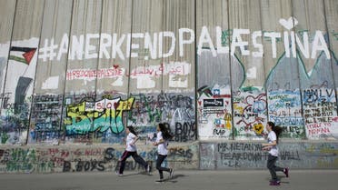  Runners taking part in the Palestine Marathon pass by the Israeli separation barrier in the West Bank city of Bethlehem, Friday, March 27, 2015. Three thousand Palestinian and international runners participated in the race that started in front of the Church of Nativity, with the course winding through the streets of Bethlehem, past the Olympic distance track course, the Israeli separation barrier and Palestinian refugee camps. (AP Photo/Nasser Nasser)