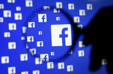 A man poses with a magnifier in front of a Facebook logo on display in this illustration taken in Sarajevo, Bosnia and Herzegovina, in this December 16, 2015, file photo. REUTERS