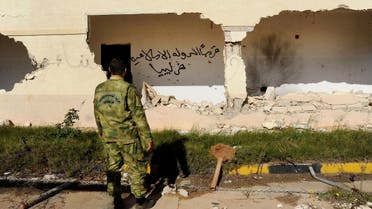 In this picture taken Wednesday, Feb. 24, 2016, A Libyan army soldier looks at damages with Arabic that reads, "soon, the Islamic State will be in Libya," in Benghazi. Libyans took to the streets in Benghazi on Tuesday, Feb. 23, 2016 honking car horns and waving Libyan flags in celebration after army units, backed by civilian fighters, cleared a major part of this eastern city of Islamic extremists, following nearly two years of deadly fighting. (AP)