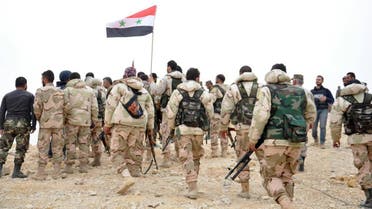 In this photo released by the Syrian official news agency SANA, Syrian soldiers gather around a Syrian national flag in Palmyra, Syria, Sunday, March 27, 2016. Syrian state media and an opposition monitoring group say government forces backed by Russian airstrikes have driven Islamic State fighters from the historic central town of Palmyra, held by the extremists since May. (SANA)