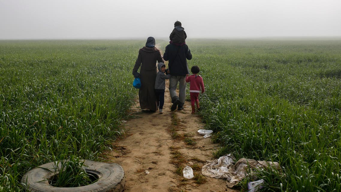 A family walks through a field at a makeshift camp for migrants and refugees at the Greek-Macedonian border near the village of Idomeni, Greece, April 4, 2016. REUTERS