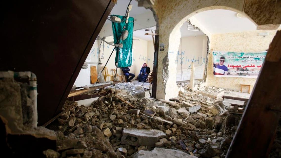 Palestinians sit inside the home of Ehab Maswada, seen on the poster, that was demolished by the Israeli army in the West Bank city of Hebron, Thursday, March 31, 2016. (File photo: AP)