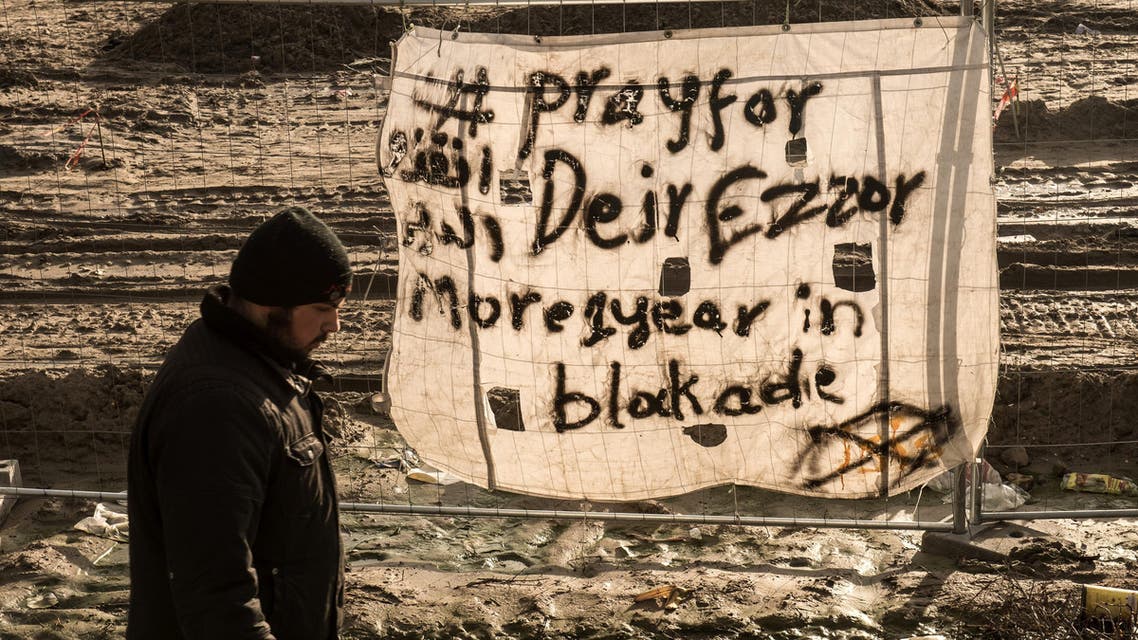 A man walks past a ‘Pray for Deir Ezzor’ at the migrant camp known as the ‘Jungle’ in Calais last December. (Picture: AFP) 