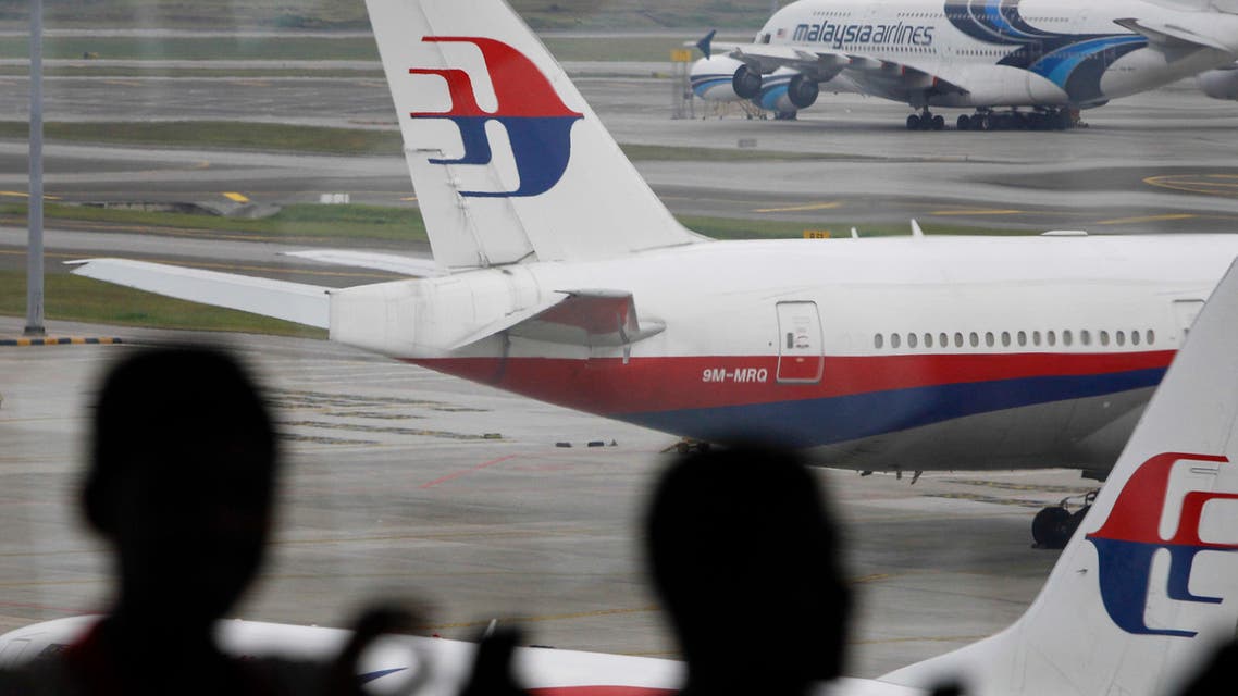 In this photo taken on Saturday, March 5, 2016, Malaysia men are silhouetted against taxied Malaysia Airlines' planes in Kuala Lumpur International Airport in Sepang, Malaysia. (AP)