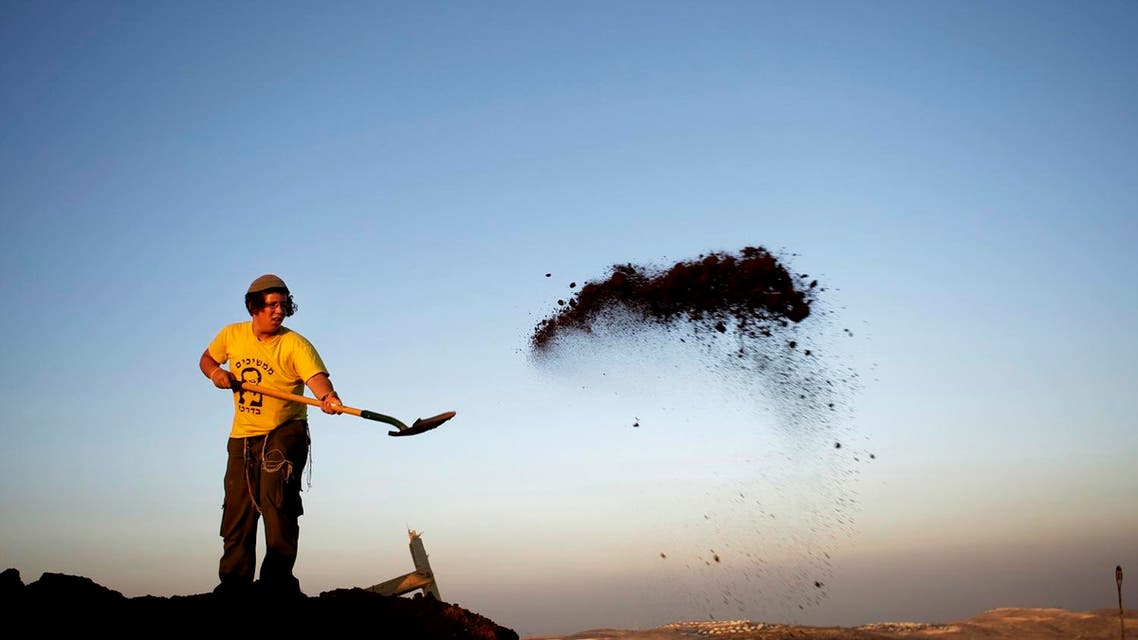 A Jewish settler removes soil from around structures demolished earlier by Israeli troops in the illegal West Bank outpost of Ramat Migron, a hilltop site near the West Bank city of Ramallah, Wednesday, June 3, 2009. (AP)