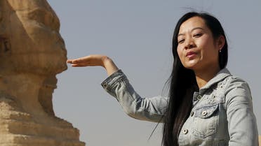 A Chinese tourist poses for a photo in front of the Sphinx at the Giza Pyramids on the outskirts of Cairo, Egypt March 2, 2016. REUTERS