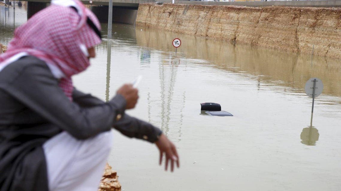 A Saudi man uses his mobile phone near a car submerged in flood waters following heavy rain, in Riyadh, Saudi Arabia November 25, 2015. (File photo: Reuters)