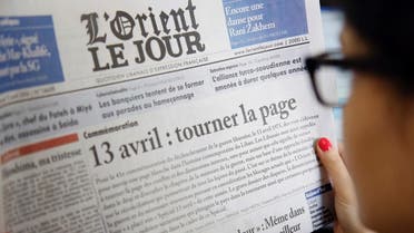 A woman holds a Lebanese newspaper with its front page appealing for readers to "turn the page" on sectarian divisions, on the 41st anniversary of the eruption of Lebanon’s civil war, on April 13, 2016. On April 13, 1975, clashes erupted in Beirut between Lebanese Christians and Palestinians, marking the beginning of the 15-year war that left more than 150,000 dead. Although the conflict officially ended in 1990, Lebanon remained plagued by instability, corruption, and bitterly divided political factions.  / AFP / ANWAR AMRO