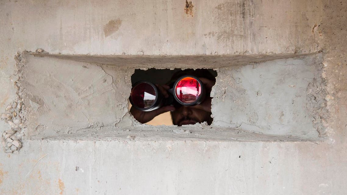 A member of Palestinian security forces looks through binoculars to the Egyptian side, as they secure the border after it was flooded from tunnels at the Palestinian side in 2013. (File photo: AP)