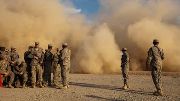 Soldiers from the 3rd Brigade Combat Team, 1st Cavalry Division watch a Blackhawk helicopter raise a sand cloud during landing as they wait at a staging area in Camp Adder to be part of the last U.S. military convoy to leave the country near Nasiriyah, Iraq on Saturday, Dec. 17, 2011. (AP)