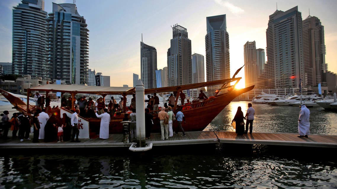 In this March 25, 2015 photo, tourists of different nationalities board a dhow for a cruise as the sun sets in the Marina neighborhood of Dubai, United Arab Emirates.