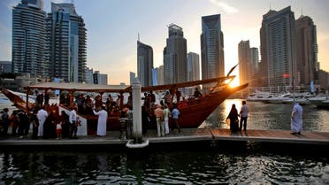 In this March 25, 2015 photo, tourists of different nationalities board a dhow for a cruise as the sun sets in the Marina neighborhood of Dubai, United Arab Emirates. 