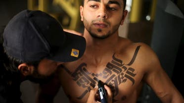 Palestinian artist Bilal Khalid paints Arabic letters on a bodybuilder in a gym in Gaza City April 12, 2016. REUTERS