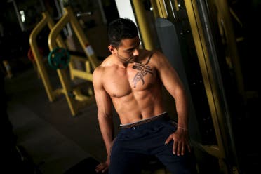 A bodybuilder reacts as his body is painted with Arabic letters by Palestinian artist Bilal Khaled in a gym in Gaza City April 12, 2016. REUTERS